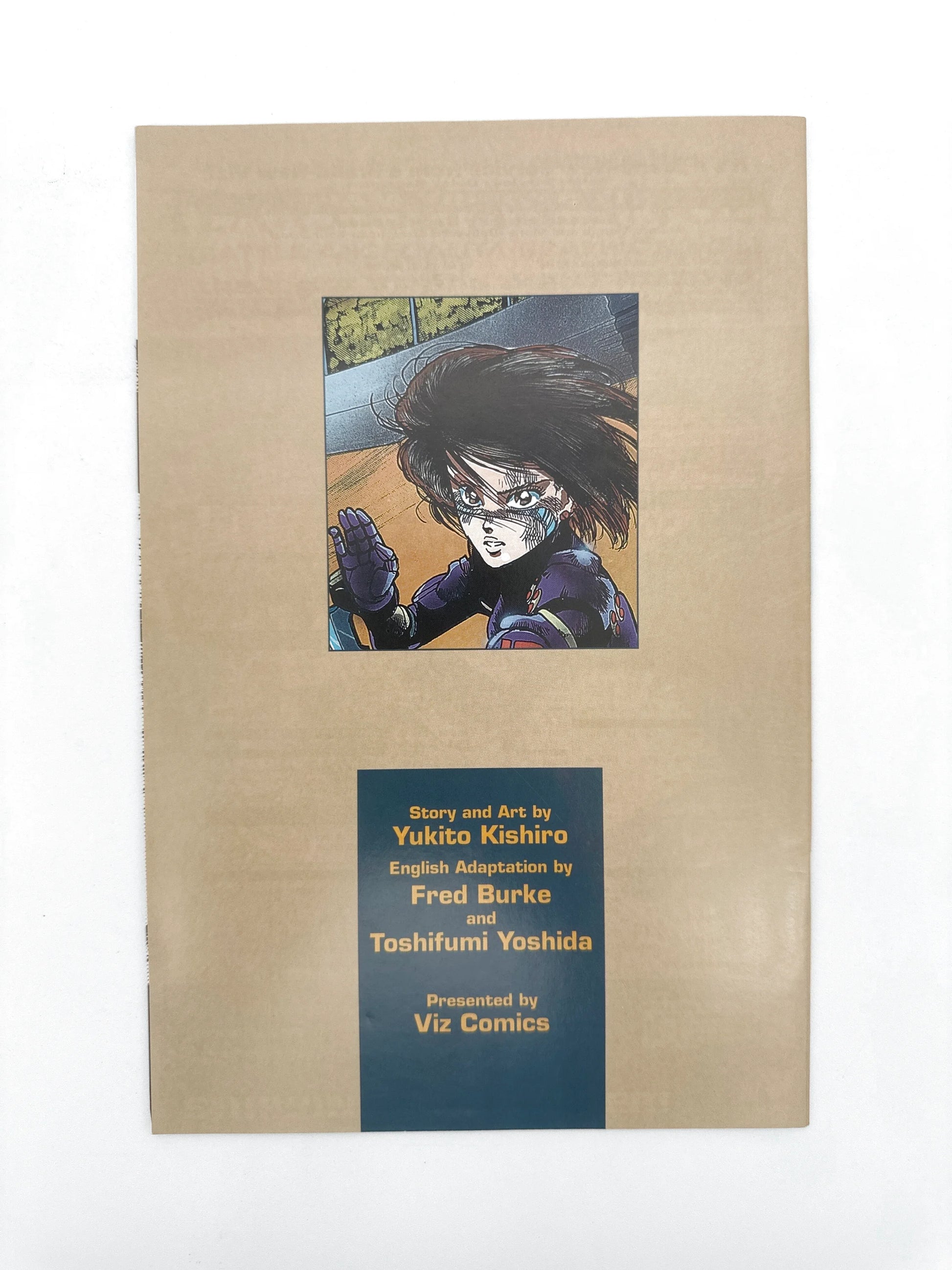A manga book, possibly the first page, featuring an illustration of a female character with a blue and black uniform and dark hair, with text attributing the story and art to Yukito Kishiro, English adaptation to Fred Burke and Toshifumi Yoshida, and presentation by Viz Comics.